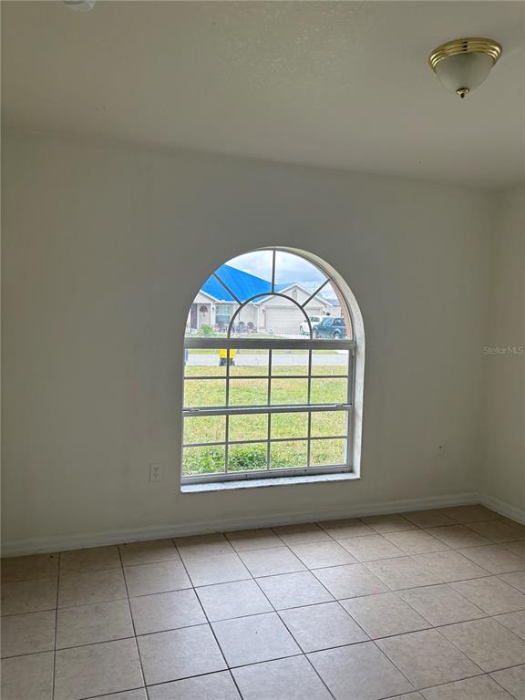 An empty room with tiled floors, white walls, and an arched window looking outside — 756 CAMEL COURT, KISSIMMEE, FL