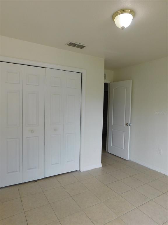 A bedroom with tile flooring, a white bi-fold closet, and an open interior door — 756 CAMEL COURT, KISSIMMEE, FL