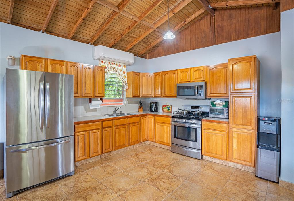 A kitchen with wood cabinets, stainless steel appliances, and a vaulted wood-paneled ceiling — 2 #8 URBANIZABLE. VILLA SOÑDA, TRUJILLO ALTO, PR