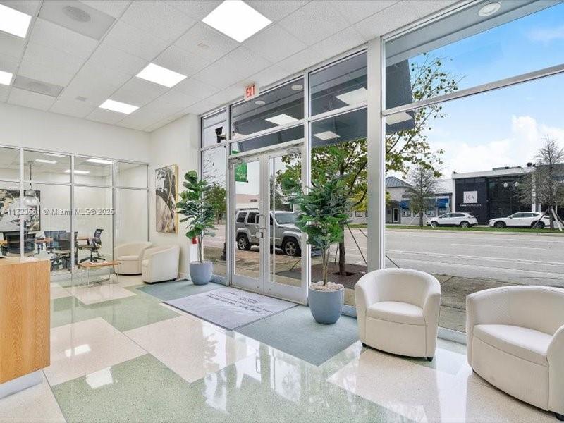 A bright office lobby features white armchairs, potted plants, glass walls, and large exterior windows — 2404 Hollywood Blvd, Hollywood FL 33020, HOLLYWOOD, FL