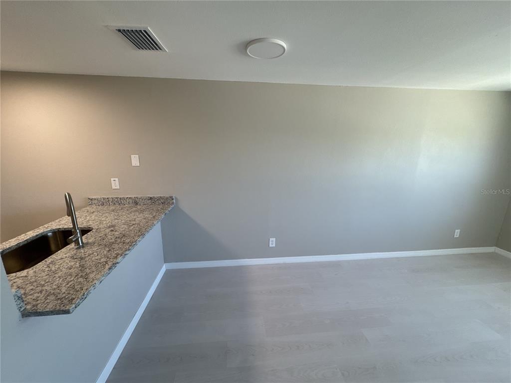 An interior view shows a kitchen counter with granite countertops and light-colored flooring — 1285 GULF BOULEVARD UNIT 5, ENGLEWOOD, FL