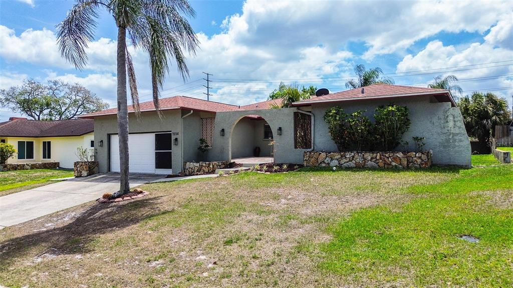 A single-story house with a stucco exterior, stone accents, and a palm tree in front — 7556 HIGH PINES COURT, PORT RICHEY, FL