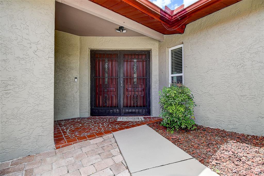 A front entryway features double doors with security grilles, a tiled porch, and a walkway — 7556 HIGH PINES COURT, PORT RICHEY, FL