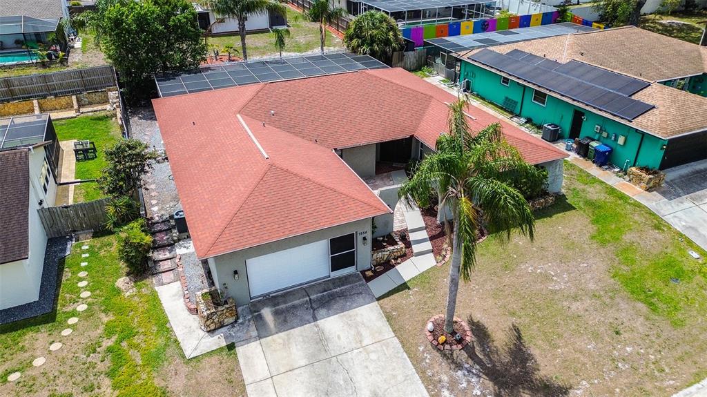 An aerial view shows a single-story house with a red roof, garage, and palm tree — 7556 HIGH PINES COURT, PORT RICHEY, FL