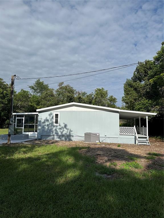 A light blue manufactured home features a screened-in porch, a side deck, and an AC unit — 18021 APPLEJACK COURT, SPRING HILL, FL