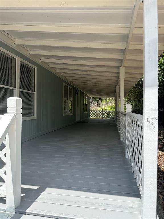 A long, covered wooden porch with white railings and lattice panels runs along a house — 18021 APPLEJACK COURT, SPRING HILL, FL