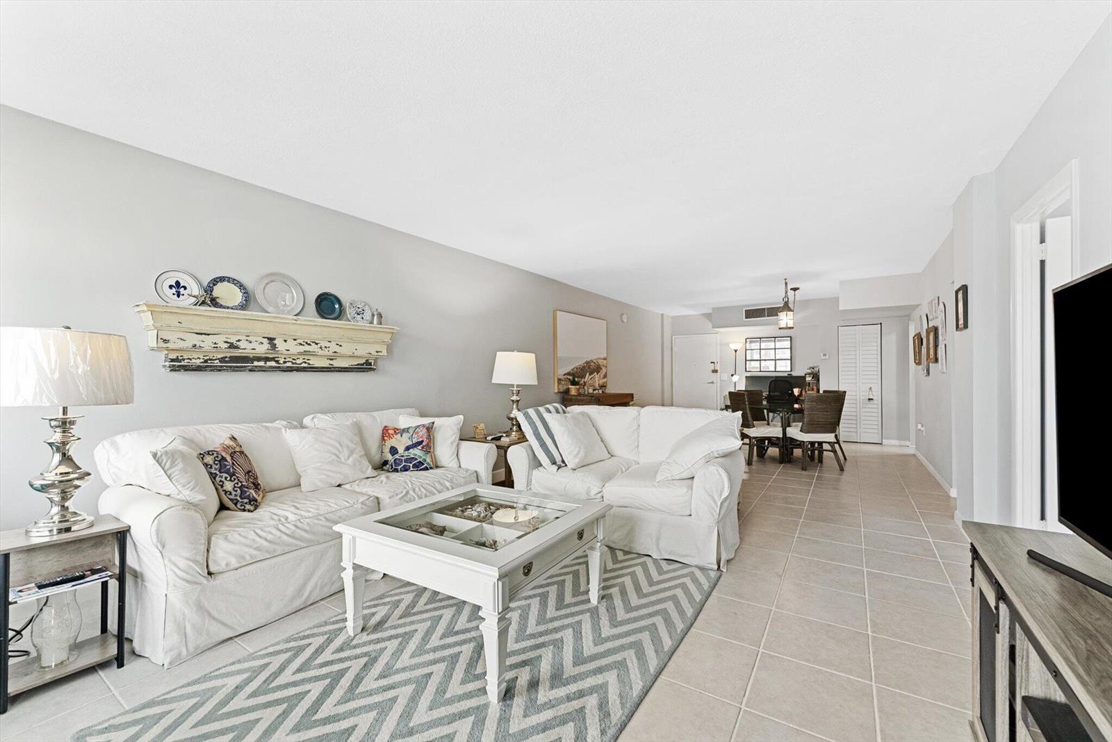 A living room with white sofas, a chevron rug, and a dining area beyond — 3450 S Ocean Boulevard # 620, Palm Beach FL 33480, PALM BEACH, FL