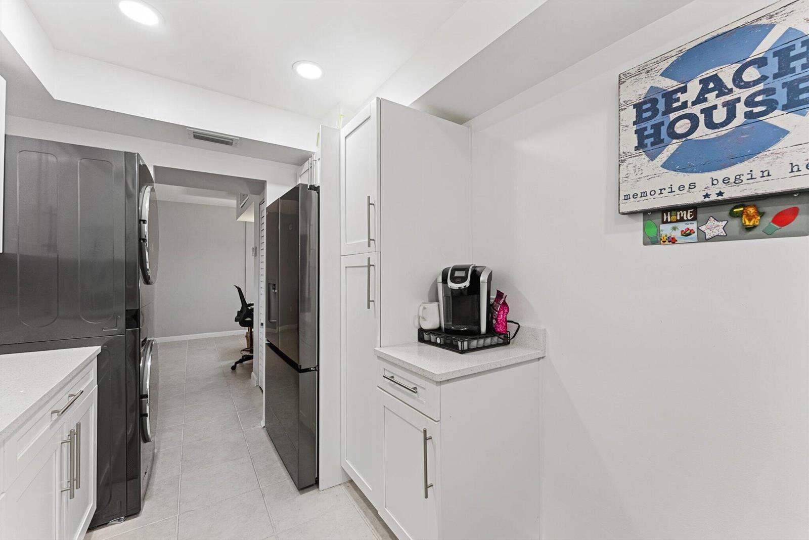 A laundry room features white cabinetry, a dark refrigerator, and a coffee station — 3450 S Ocean Boulevard # 620, Palm Beach FL 33480, PALM BEACH, FL