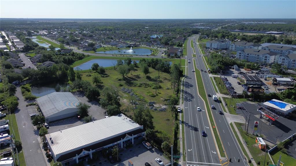 An aerial view shows a commercial area, a vacant lot, and a multi-lane road — 6347 NARCOOSSEE ROAD, ORLANDO, FL