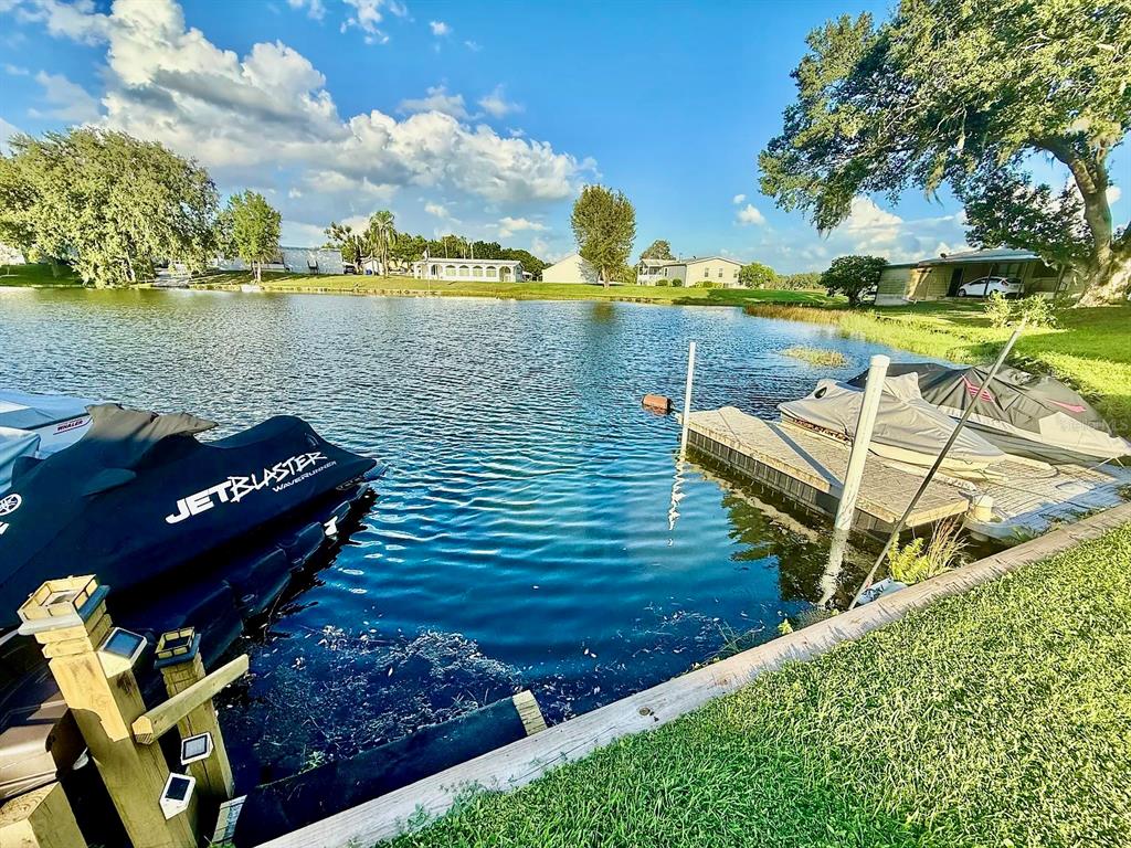 A view of a lake with a wooden dock and two personal watercraft — 16 W PALM CIRCLE, LAKE PLACID, FL