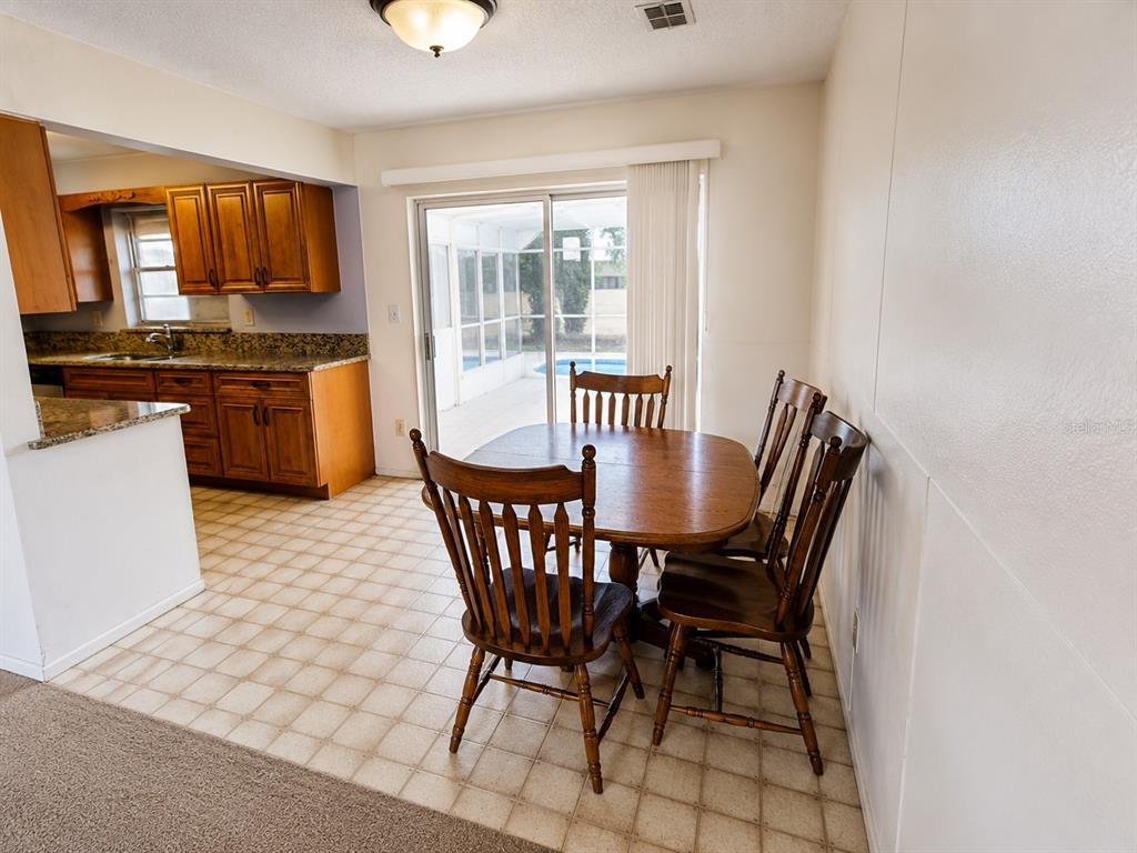 A dining area with a wooden table and chairs sits next to a kitchen with cabinets — 539 IMPERIAL AVENUE, MELBOURNE, FL