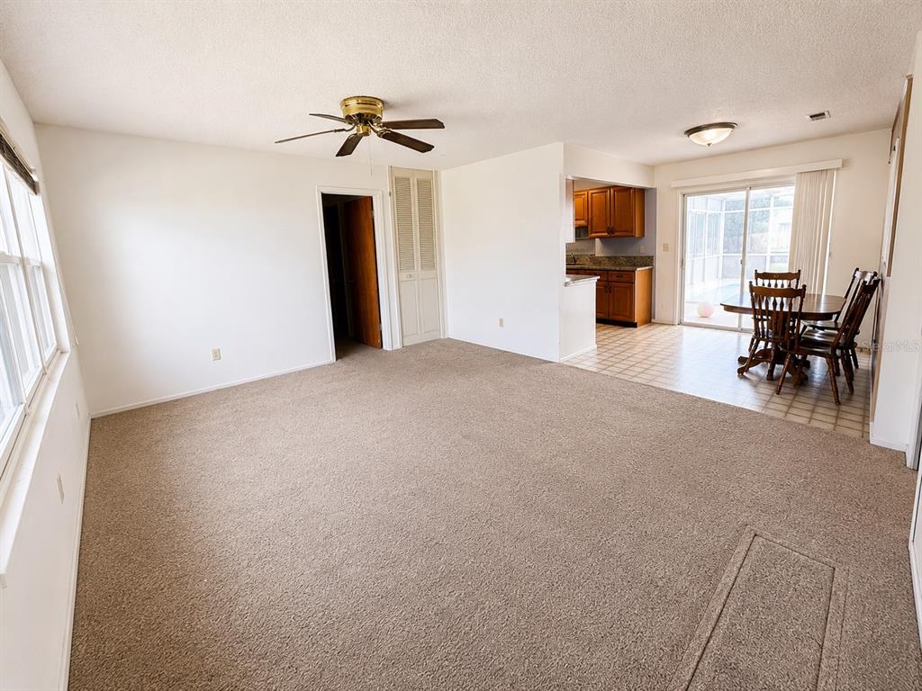 A carpeted living room opens to a dining area and kitchen with wood cabinets — 539 IMPERIAL AVENUE, MELBOURNE, FL