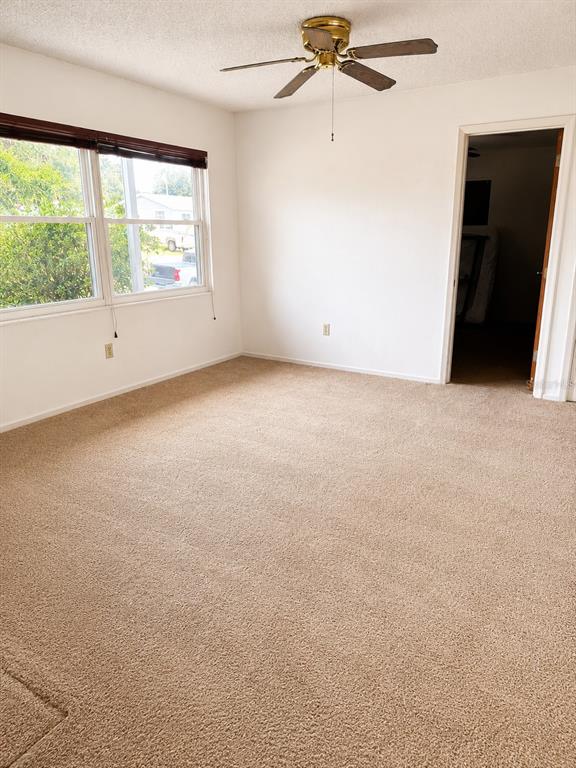 An empty bedroom features beige carpeting, white walls, a ceiling fan, and a window — 539 IMPERIAL AVENUE, MELBOURNE, FL