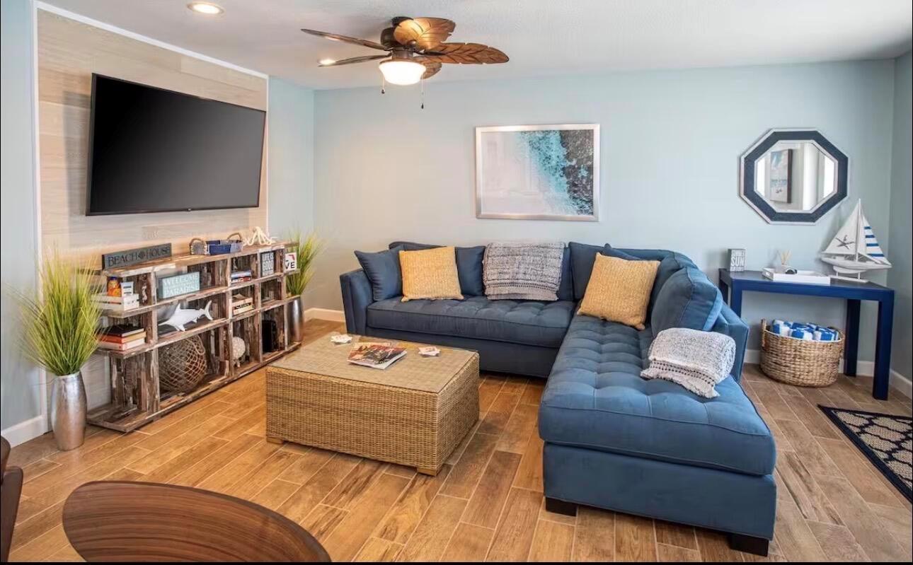 A living room features a blue sectional sofa, a wicker coffee table, and a television — 85 S Las Olas Drive, Jensen Beach FL 34957, JENSEN BEACH, FL
