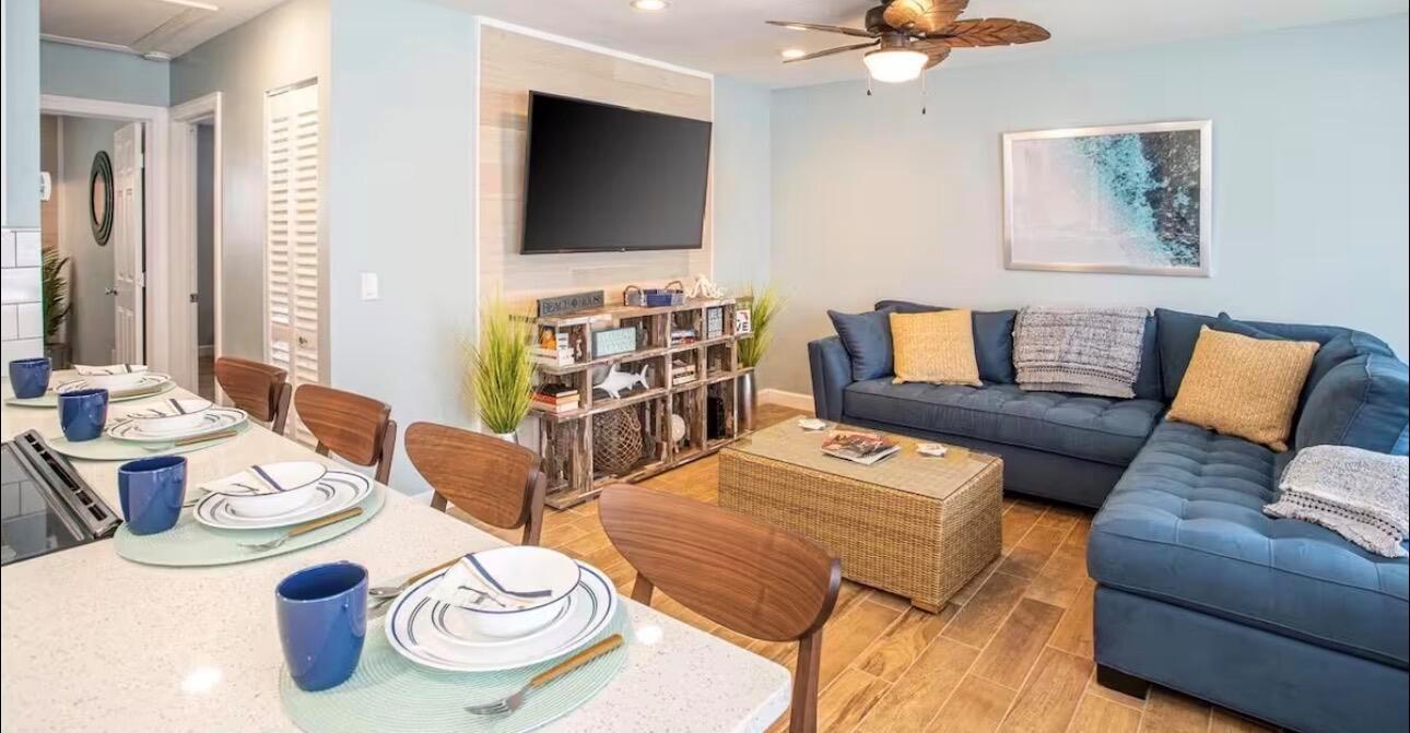 An open-concept living and dining area features a blue sectional sofa and a kitchen island — 85 S Las Olas Drive, Jensen Beach FL 34957, JENSEN BEACH, FL