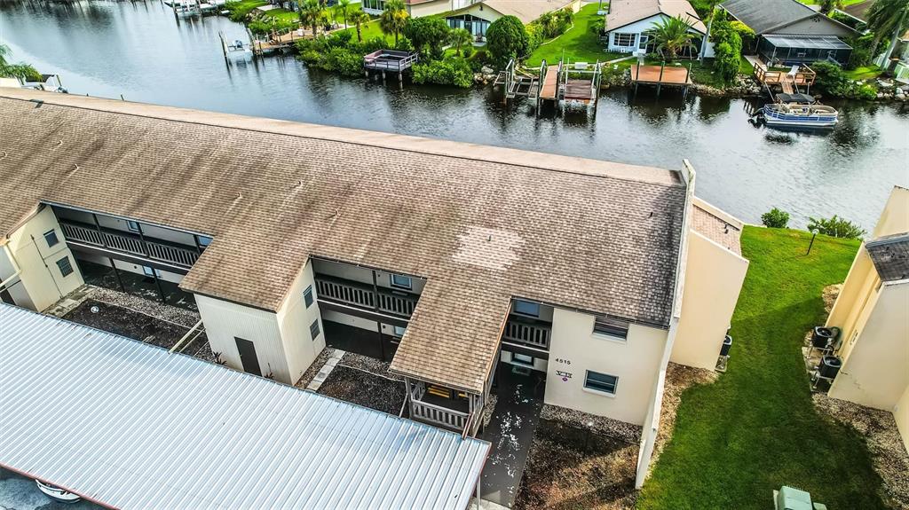 An aerial view shows a multi-story apartment building with a shingled roof near a canal — 4515 MARINE PARKWAY UNIT 206, NEW PORT RICHEY, FL