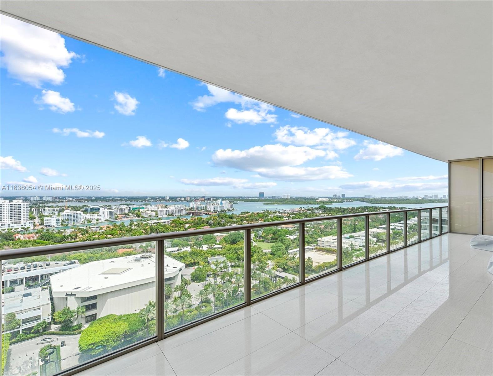 A spacious balcony features white tile flooring, a glass railing, and panoramic city and water views — 9705 Collins Ave # 1905N, Bal Harbour FL 33154, BAL HARBOUR, FL