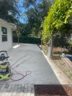 A concrete patio extends from the side of a white house toward a garden area — 7890 MARX DRIVE, NORTH FORT MYERS, FL