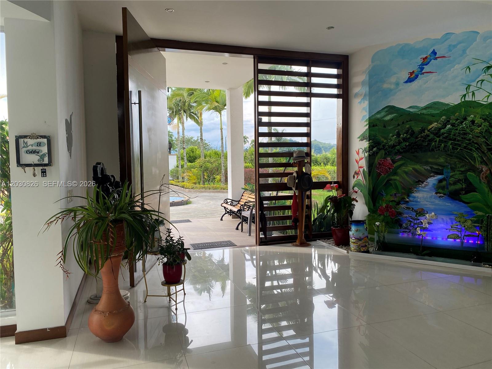 An entryway features a large mural, polished tile floors, and an open door to a patio — Sector Pavas Malabar Conjunto Chambery Casa 11, 0, FL