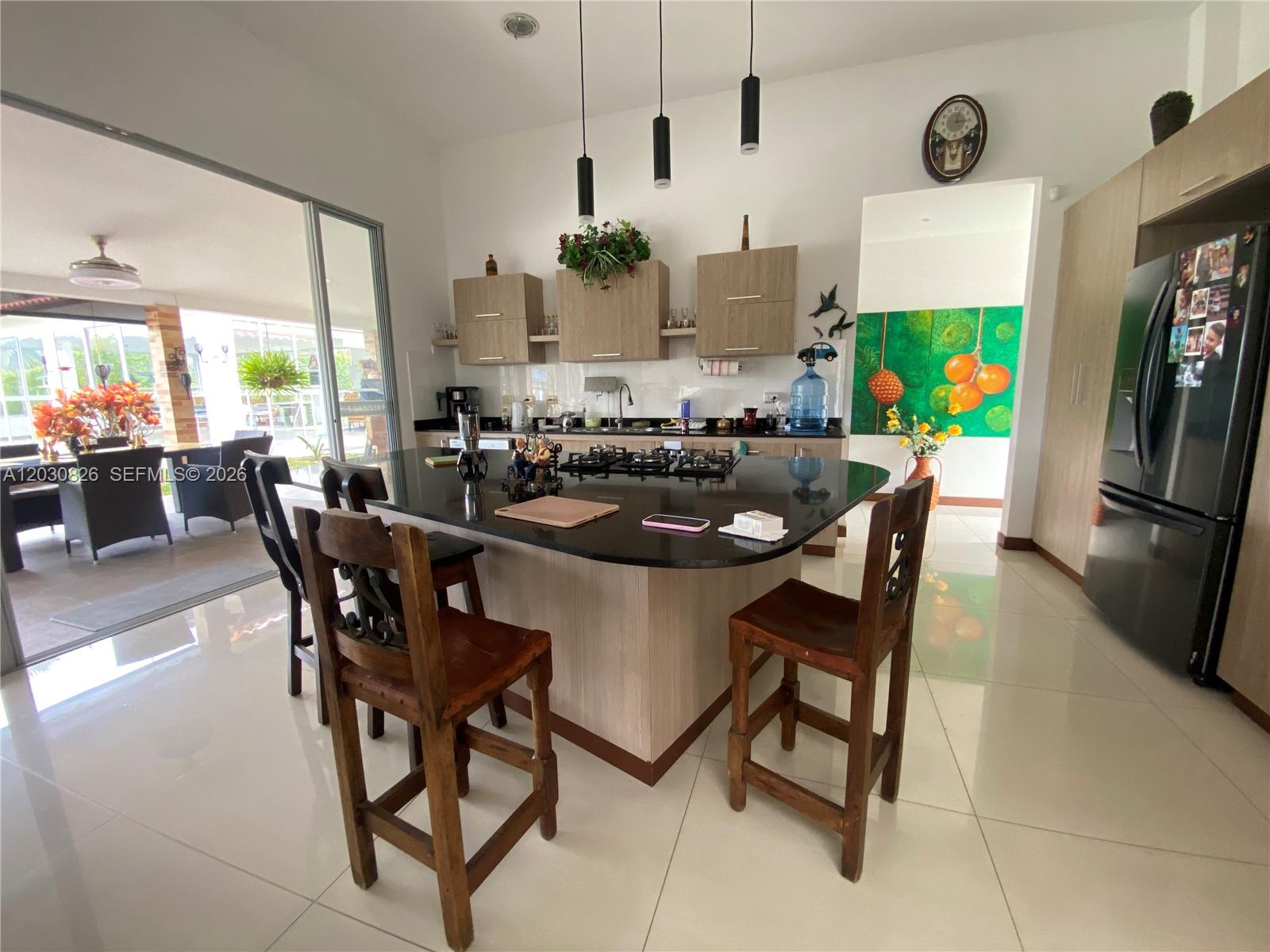 A modern kitchen features a black island, wooden bar stools, and light-colored tile flooring — Sector Pavas Malabar Conjunto Chambery Casa 11, 0, FL