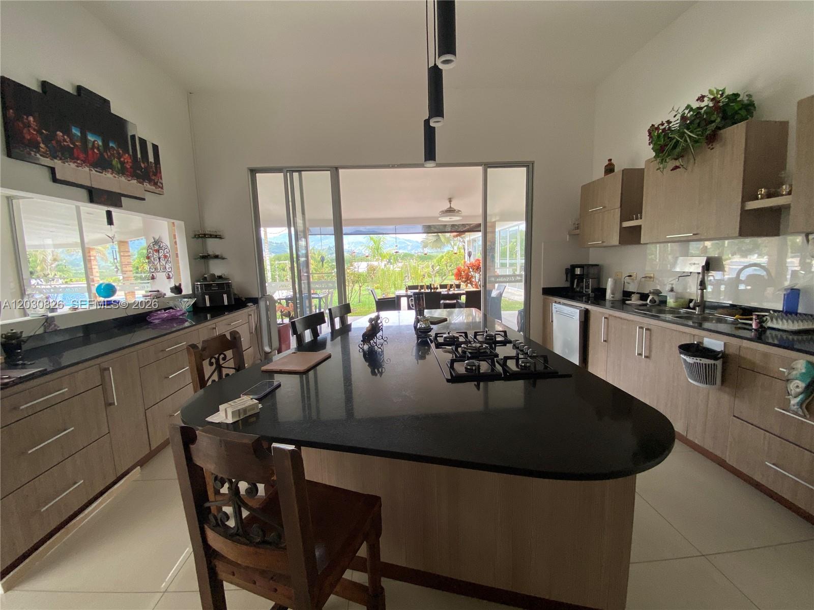 A kitchen features a large black island with a gas cooktop and light wood cabinetry — Sector Pavas Malabar Conjunto Chambery Casa 11, 0, FL
