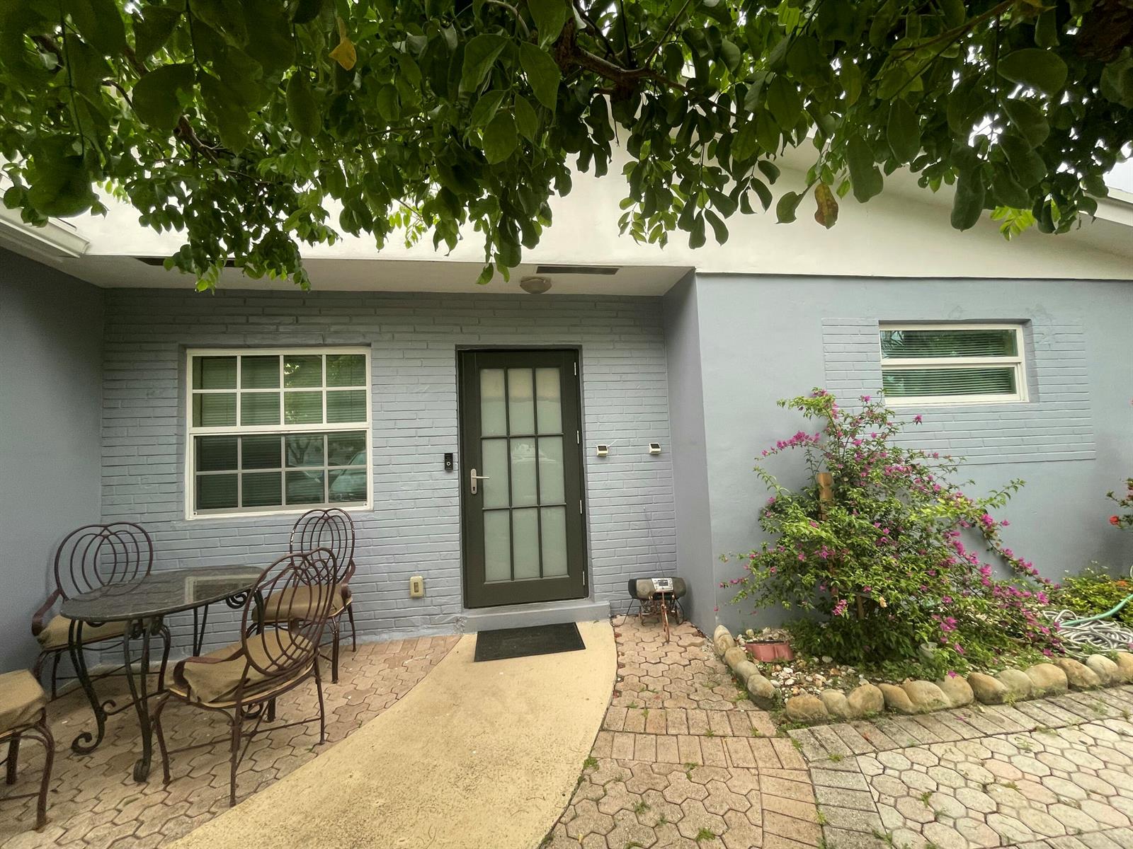 A gray brick house exterior features a front door, patio furniture, and a landscaped garden — 3850 NE 12th Terrace, Pompano Beach FL 33064, POMPANO BEACH, FL