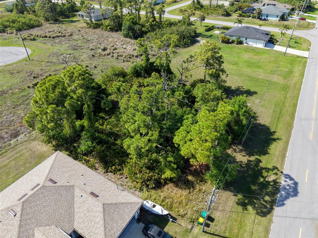 An aerial view shows a wooded vacant lot situated between a house and a road — 274 SWEETWATER DRIVE, ROTONDA WEST, FL