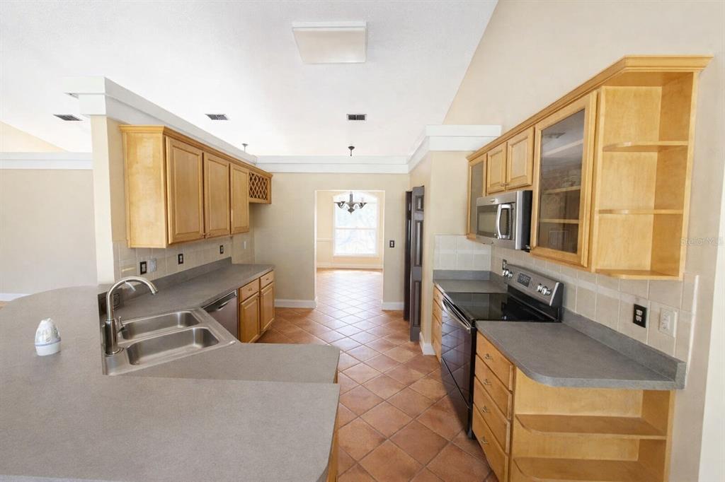 A kitchen with light wood cabinets, gray countertops, tile flooring, and a breakfast bar — 791 SE 142 AVENUE, WILLISTON, FL