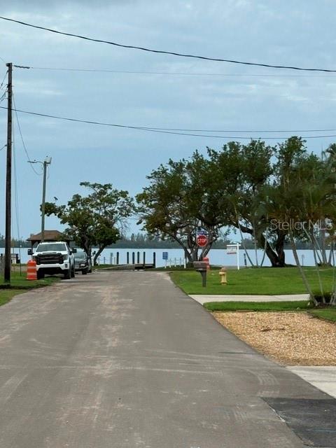 A paved road leads toward a waterfront area with trees, a stop sign, and parked vehicles — 4519 106TH STREET W, BRADENTON, FL