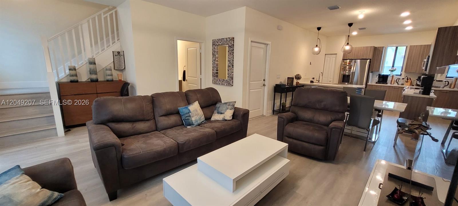 This open-concept living room features a brown sofa, recliner, white coffee table, and kitchen area — 4682 NW 83rd Ave, Doral FL 33166, DORAL, FL