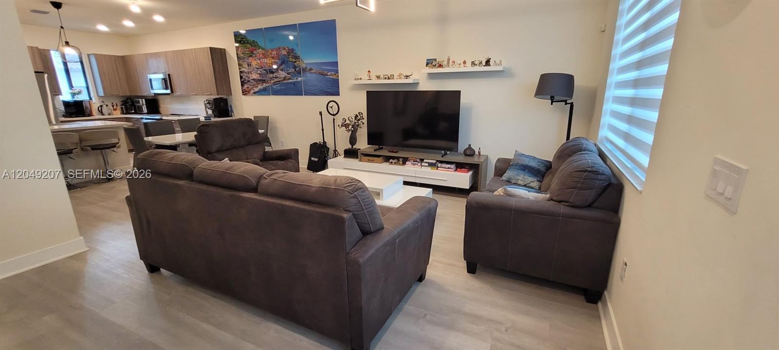 A living room features gray sofas, a television on a console, and an open kitchen — 4682 NW 83rd Ave, Doral FL 33166, DORAL, FL