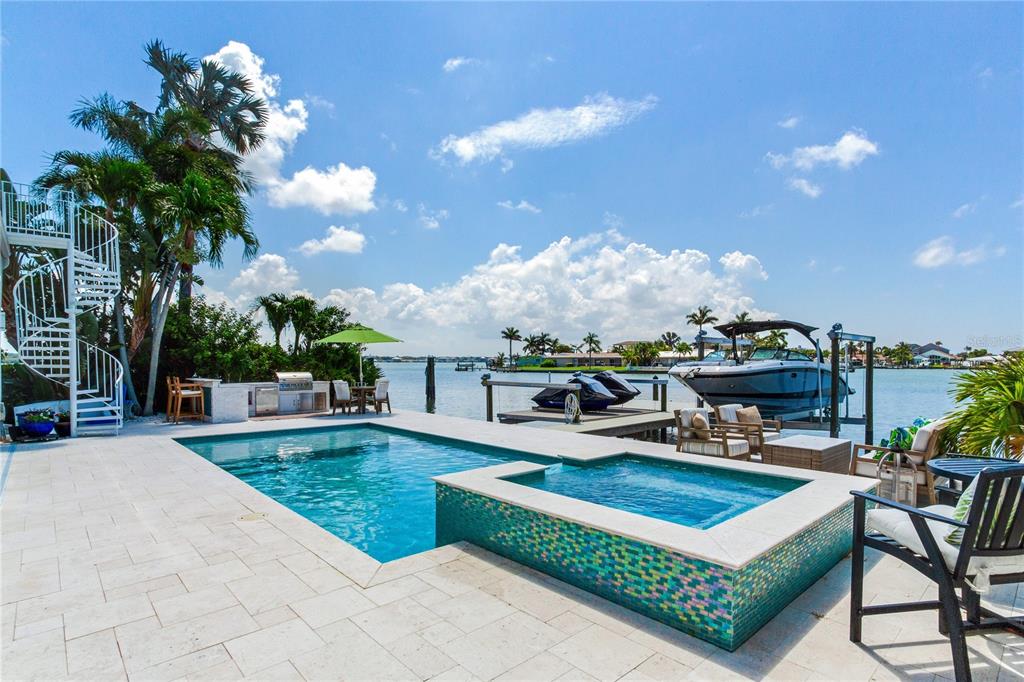 A waterfront patio features a swimming pool, a spa, a spiral staircase, and a boat dock — 17081 DOLPHIN DRIVE, NORTH REDINGTON BEACH, FL