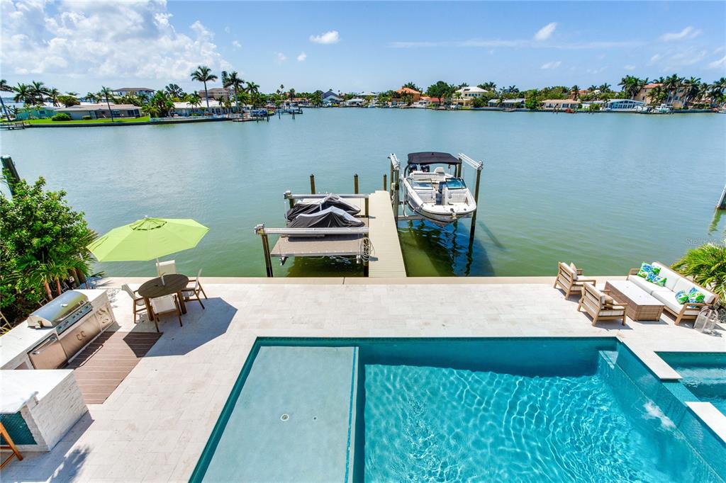 An elevated view of a waterfront patio featuring a swimming pool, boat dock, and grill — 17081 DOLPHIN DRIVE, NORTH REDINGTON BEACH, FL