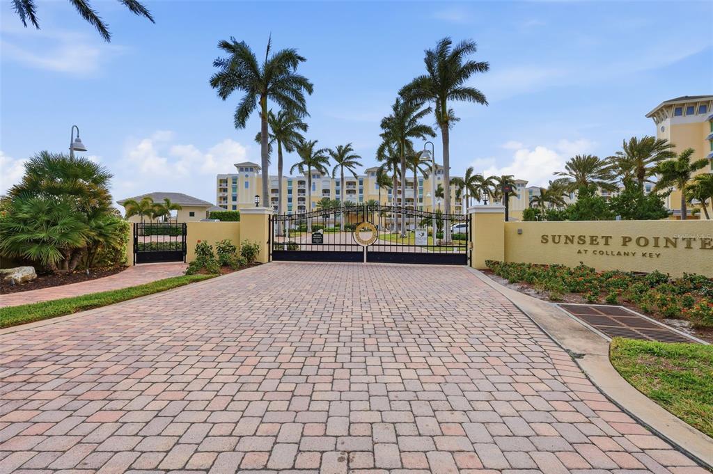 A gated entrance with a brick driveway leads to a multi-story building and palm trees — 800 COLLANY ROAD UNIT 302, ST PETERSBURG, FL