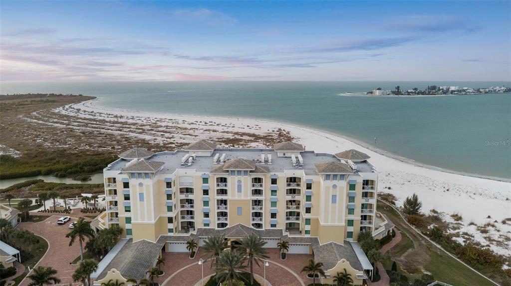 An aerial view of a multi-story beachfront condominium building with a paved circular driveway — 800 COLLANY ROAD UNIT 302, ST PETERSBURG, FL