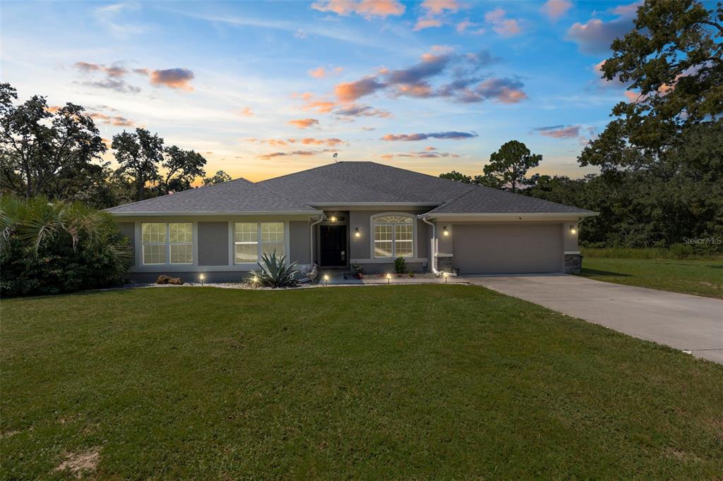 A living room features a stone fireplace, a large television, and light-colored wood flooring — 18209 MERWYN CIR, WEEKI WACHEE, FL