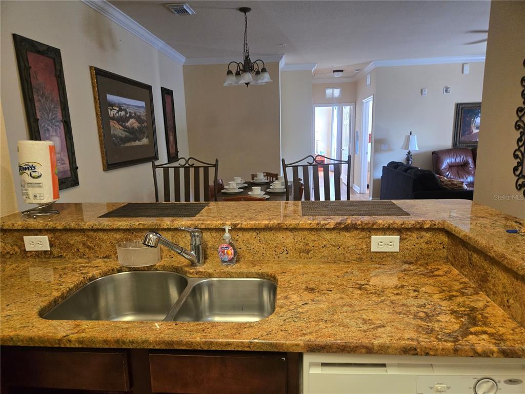 A kitchen sink with granite countertops overlooks a dining area and living room — 1301 TUSCAN TERRACE UNIT 9408, DAVENPORT, FL