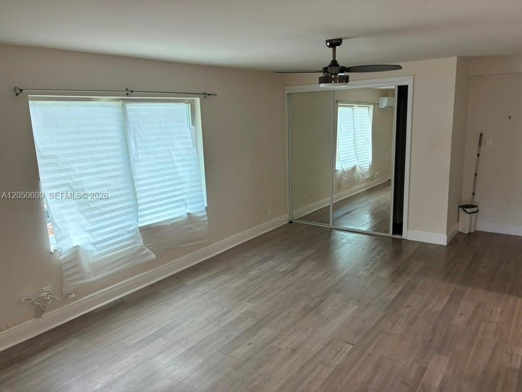 A bedroom features light-colored walls, wood-look flooring, a ceiling fan, and mirrored closet doors — 3700 NE 13th Ter # 1, Pompano Beach FL 33064, POMPANO BEACH, FL