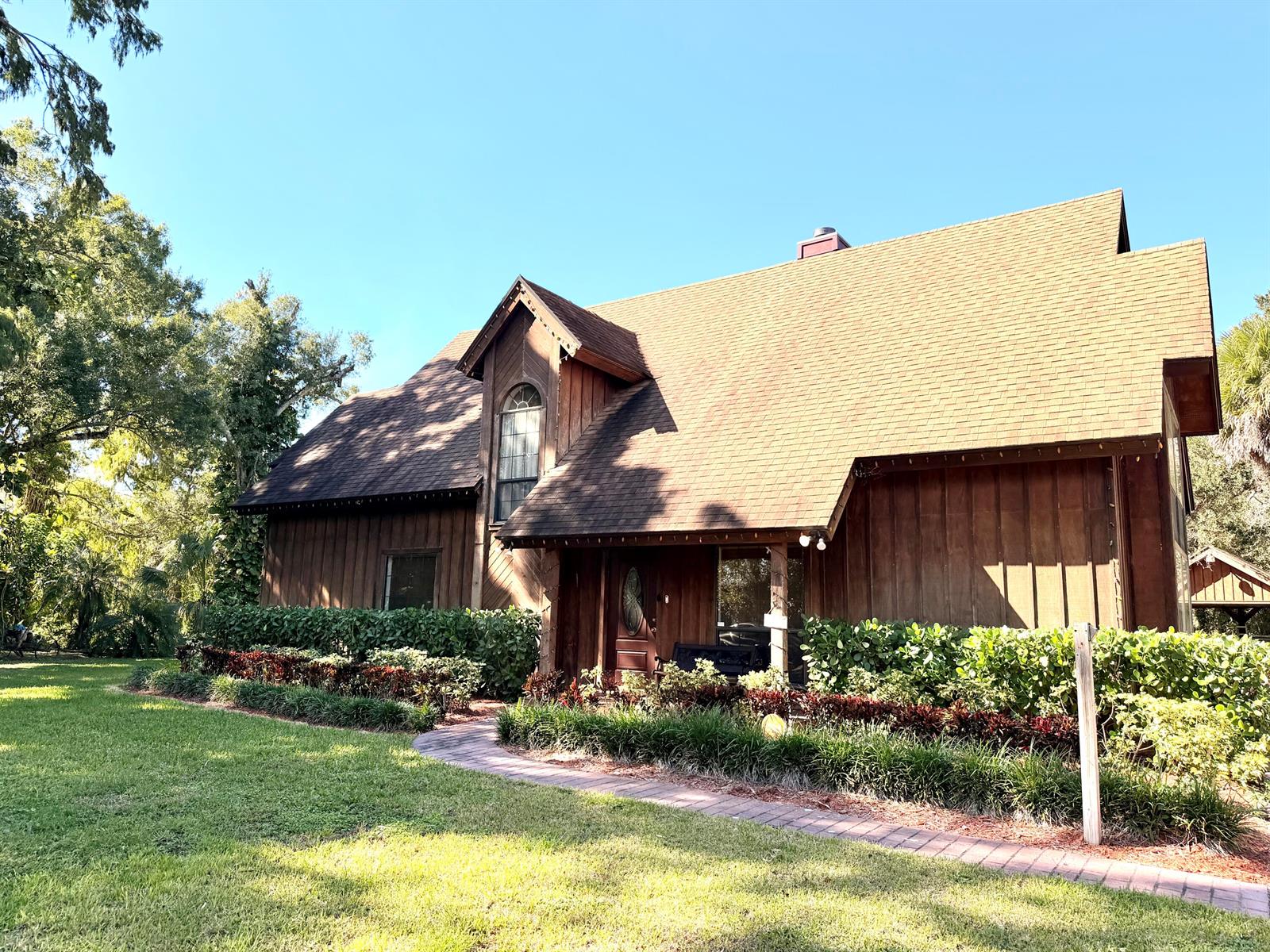 A two-story wooden house with a steep shingled roof and a brick walkway — 505 SE 18th Way, Okeechobee FL 34974, OKEECHOBEE, FL