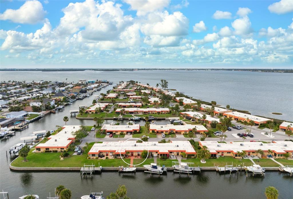 An aerial view shows a waterfront residential complex with boat slips and a circled unit — 9527 AZURE COVE, BRADENTON, FL