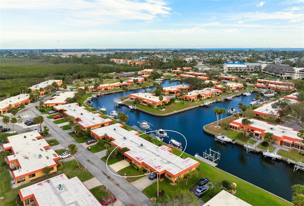 An aerial view shows a waterfront residential complex with a circled single-story building — 9527 AZURE COVE, BRADENTON, FL