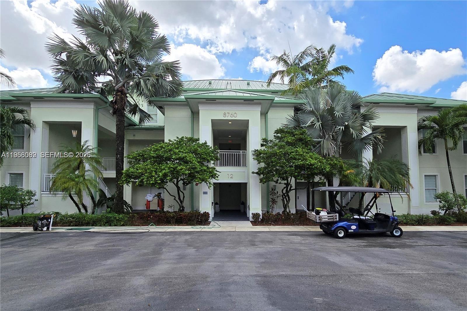 A multi-story residential building with a green roof, palm trees, and a parked golf cart — 5300 NW 87th Ave # 1209, Doral FL 33178, DORAL, FL