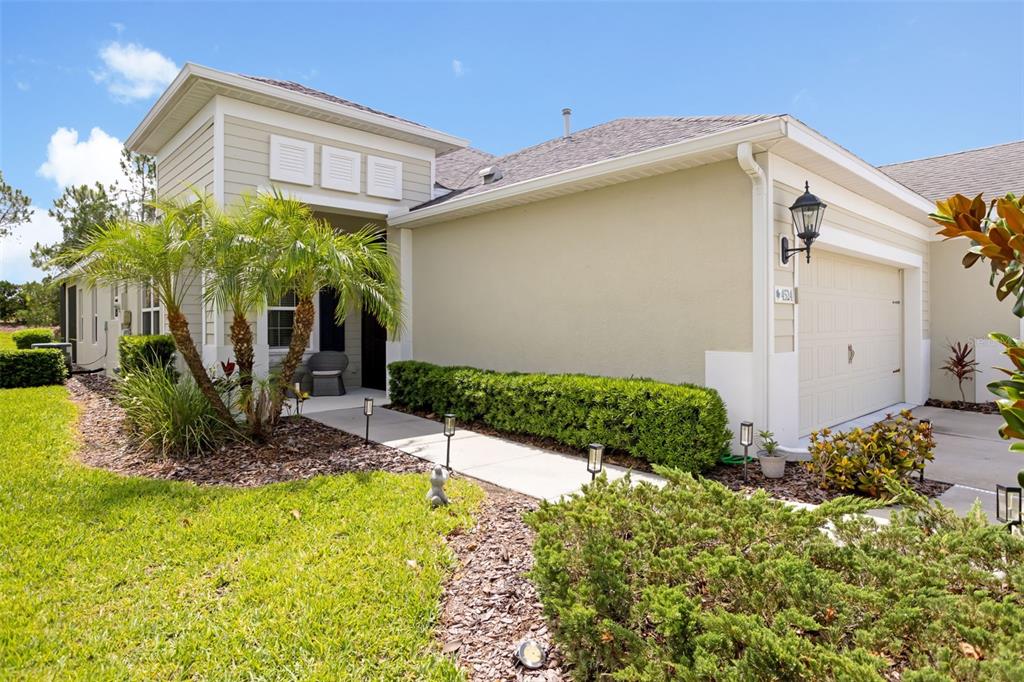 A single-story house exterior features tan siding, a garage, a walkway, and landscaping — 4524 DEEP CREEK TERRACE, PARRISH, FL