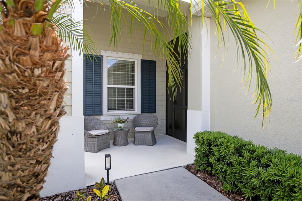 A covered front porch features two wicker chairs, a small table, and blue shutters — 4524 DEEP CREEK TERRACE, PARRISH, FL