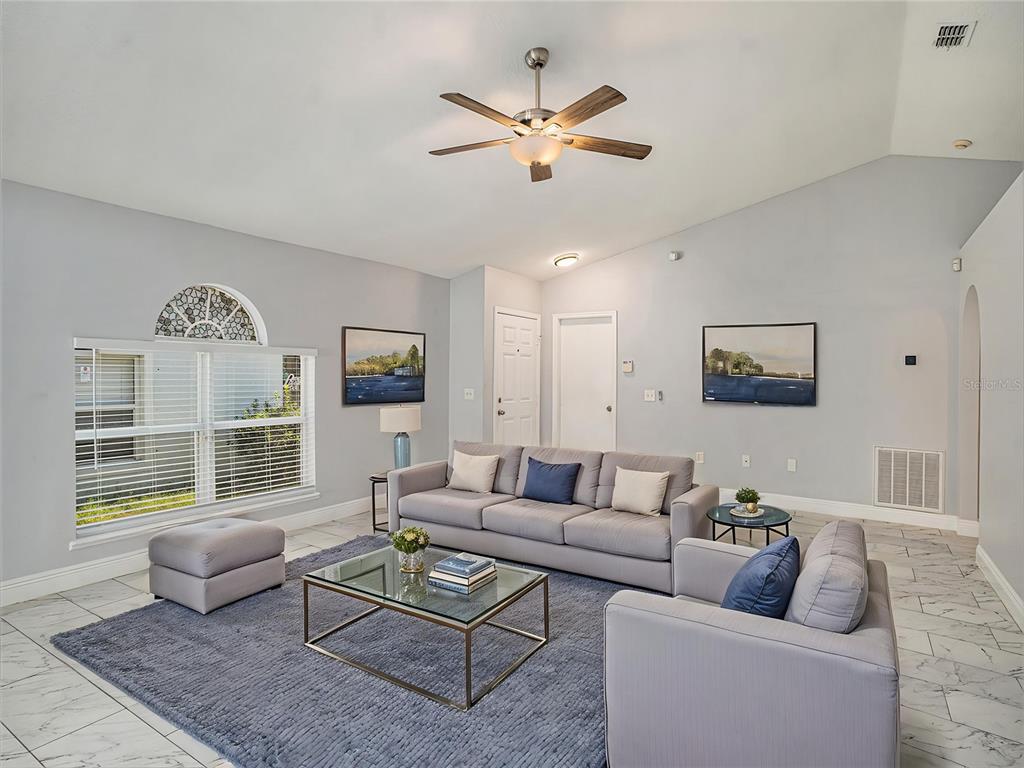 A living room features light gray walls, tile flooring, a blue rug, and modern furniture — 11433 IVY FLOWER LOOP, RIVERVIEW, FL