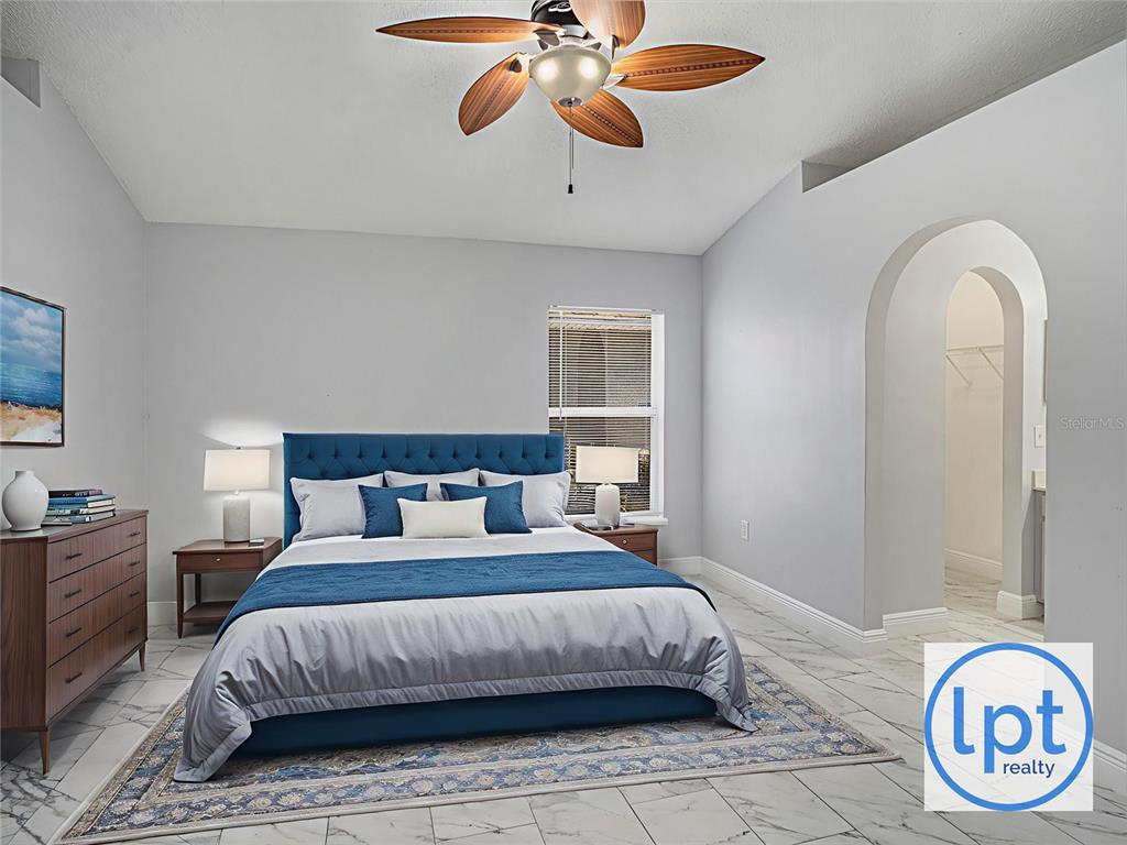 A bedroom features a blue upholstered bed, tile flooring, and an arched doorway — 11433 IVY FLOWER LOOP, RIVERVIEW, FL