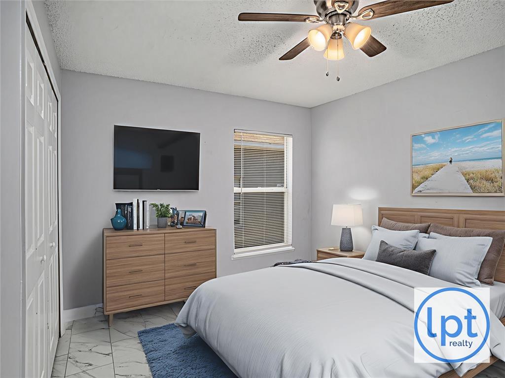 A bedroom features a bed, dresser, wall-mounted television, ceiling fan, and light-colored tile flooring — 11433 IVY FLOWER LOOP, RIVERVIEW, FL