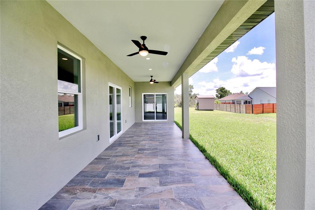 A covered patio with tile flooring, two ceiling fans, and a view of the backyard — 4631 MIGNON DRIVE, SEBRING, FL