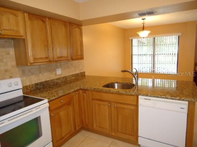 A kitchen features light wood cabinets, granite countertops, a white stove, and a white dishwasher — 4012 CIRCLEWOOD COURT, TAMPA, FL