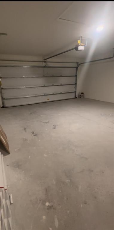 An empty garage with a concrete floor, white walls, and a sectional overhead door — 247 SUMMERLIN LOOP, HAINES CITY, FL